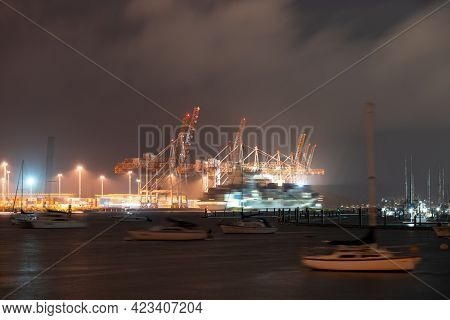 Nicght Scnes Of Port Of Tauranga Wharves At Night With  Bllurred Moving Ships, Boats And Container C