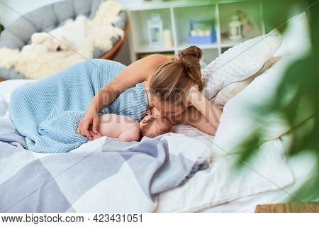 Happy Young Woman Feeds Breast Milk, Kissed And Hugs Baby. A Mother Is Breastfeeding Newborn Baby Wh