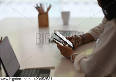 Cropped Shot Of Young Female Freelancer Using Smartphone In Modern Office.