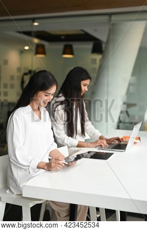 Portrait Of Two Young Female Brainstorming On Their Project  With Laptop And Tablet In Modern Living