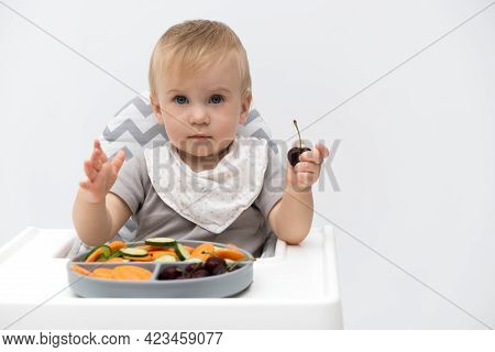 Caucasian Baby About 1 Year Old, Eating Fresh Vegetables At High Chair On White Background.self-feed