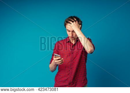 Scared Young Guy Holding A Smartphone In His Hand Covers His Face With His Hand In Shock At The Erro