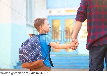 Dad Walks The Child To School. He Encourages The Student To Accompany Him To School. A Caring Father