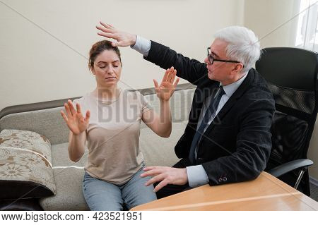 Mature Gray-haired Man Hypnotizes Caucasian Woman During Hypnotherapy Session. The Psychologist Uses