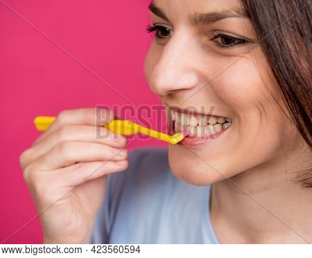 Beautiful Happy Young Woman With Single Tufted Toothbrush On Blank Pink Background