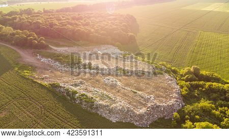 Aerial Shot Of Big Rubbish Pile Lying Among Field In Countryside. Flying Over Garbage Truck Dumping 