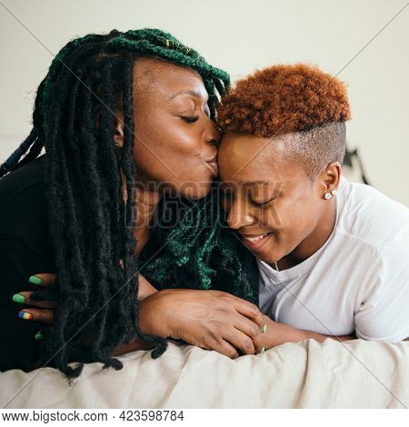 Happy lesbian couple smooching in bed
