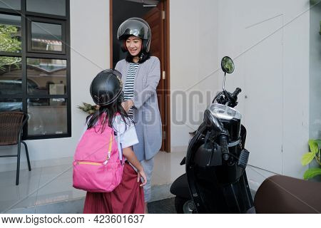 Asian Mother Fasten Her Daughter Helmet Before Going To School