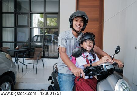 Father Taking His Daughter To School By Motorcycle In The Morning