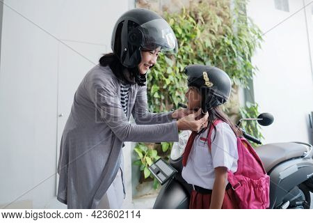Mother Taking Her Daughter To School By Motorcycle In The Morning