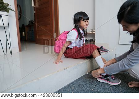 Mother Help Her Daughter To Wear A Shoes In The Morning