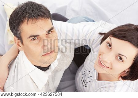 Upper View Of Portrait Of Caucasian Family Couple With Pregnant Woman Sitting Embraced Against White