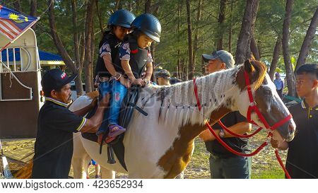 Labuan,malaysia-sept 1,2019:children In Helmet Sitting On Horse And Riding Together Outdoor Park At 