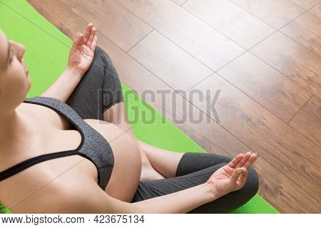 Beautiful Young Pregnant Woman Sitting On Mat In Yoga Pose At The Home. Pregnancy Yoga And Fitness C