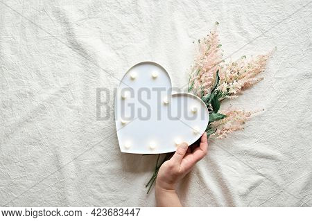 Hand With Heart Lightbox And Wild Flowers . Flat Lay On Off White Textile. Pale Pink Prachtspiere Fl