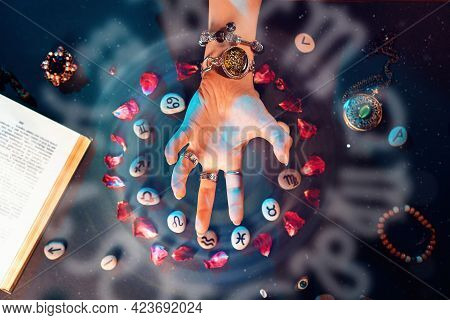 Astrology And Horoscope. A Woman's Hand Conjures Stones With The Signs Of The Zodiac, Laid Out In A 