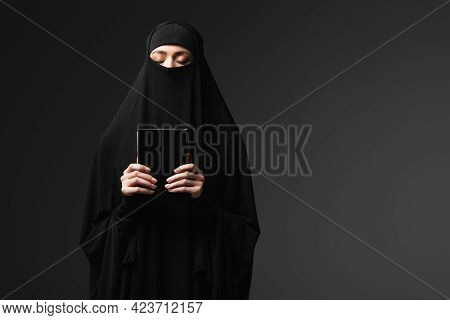 Muslim Woman Holding Koran While Praying Isolated On Black