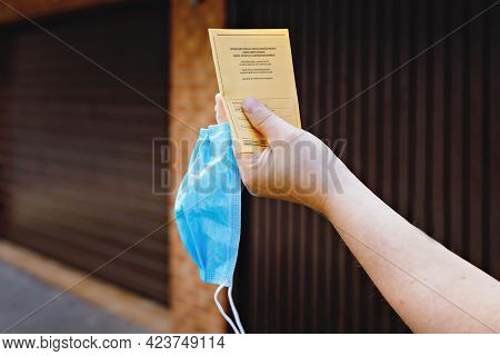 Closeup Of Man Holding German Inernational Certificate Of The Vaccination And Medical Mask. Adult Sh