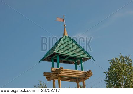 old fire wooden tower of logs and boards on the background of nature and blue sky with white clouds. 