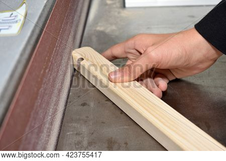 Craftsman Grinds Piece Of Wood On A Belt Sander - Close-up Carpenter
