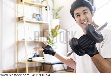 Asian Caucasian Man Hold Dumbbell In Home Training Exercise Bodyweight Trainer Indoors Workout Sport