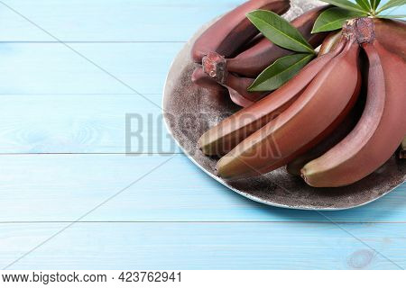 Tasty Red Baby Bananas On Light Blue Wooden Table. Space For Text