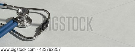 Metal Blue Sthethoscope On Blue Gray Background With Copyspace. Medicine Banner With Hospital Tool.