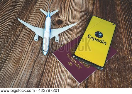 Expedia Logo Displayed On Phone Screen With Plane And Passport
