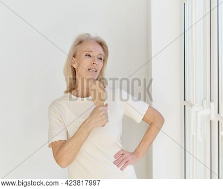 Happy Carefree Mature Woman With Hairbrush As Mic Singing Her Favourite Song And Having Fun At Home.