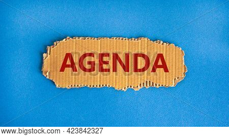 Agenda And Business Symbol. The Concept Word 'agenda' On The Piece Of Cardboard. Beautiful Blue Back