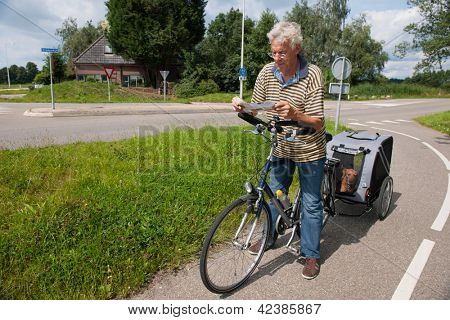 Elderly Biker with dog car is reading the route map
