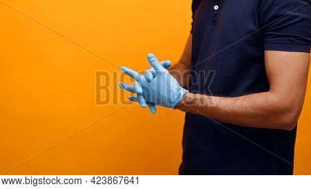Hands Of A Man Wearing Gloves. Dressed In A Blue Shirt Face Is Not Seen In The Shot. Yellow Backgrou
