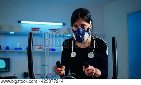 Tired Athlete Woman Training On Cross Trainer Increasing Rhythm Of Exercises Wearing Mask And Medica