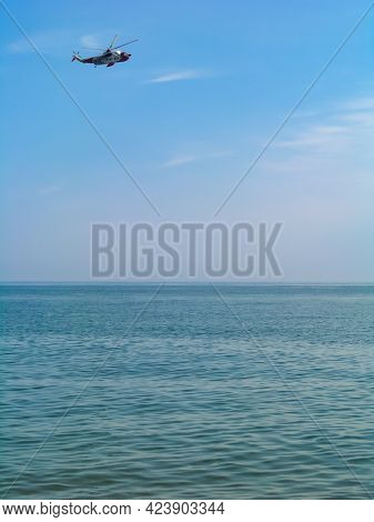 A View Of A Sunny Beach With A Town Line, A Few Beachgoers And A Calm Emerald Sea
