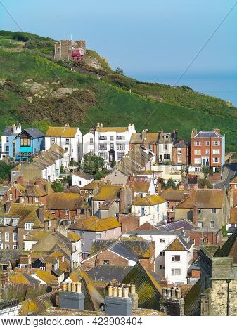 A View Of A Sunny Beach With A Town Line, A Few Beachgoers And A Calm Emerald Sea