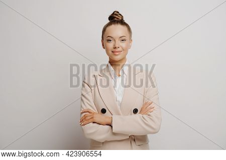 Picture Of Young Beautiful Woman Manager In Beige Suit And White Shirt With Crossed Arms, Slightly S