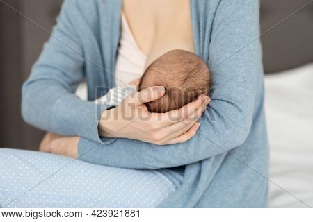 Unrecognizable Mother Holding And Breastfeeding Her Newborn Baby At Home