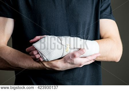The Man Supports The Bandaged Arm. Sports Arm Injury. Primary Care, The Arm Is Tightly Fixed With An