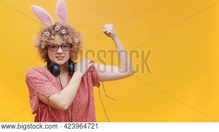 Beautiful Girl Wearing Cute Bunny Ears Hairband And Nerdy Spectacles Showing Her Strong Arm. Headpho