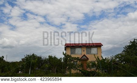 Farmhouse Rooftop Against Blue Sky With White Fluffy Clouds. Summer Daytime Landscape With Village H