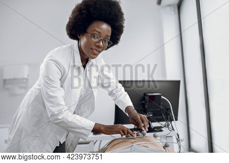Close Up Portrait Of Young Pleasant Afro American Woman Doctor Gp Cardiologist, Sticking Ecg Electro