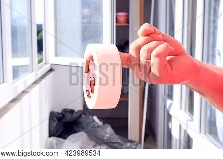 The Concept Of Self-repair. A Man's Hand Holds A Masking Tape On The Background Of An Open Balcony W