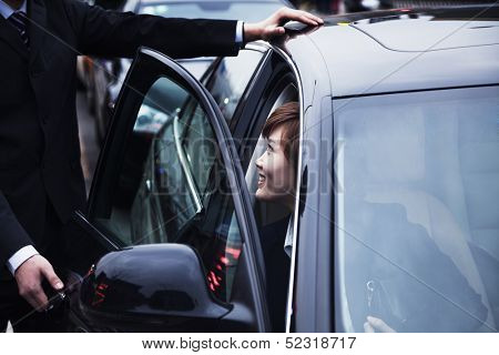 Businessman opening car door for businesswoman