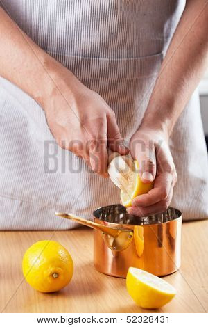 man squeezing lemon into a copper pot