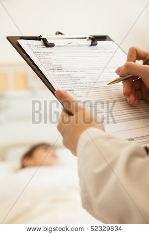 Close up of doctor writing on a medical chart 