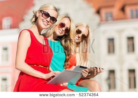 holidays and tourism concept - beautiful blonde girls toursits looking into tablet pc in the city