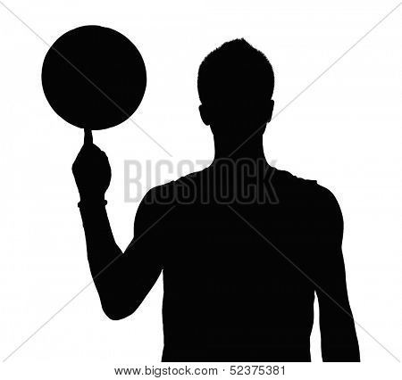 Silhouette of basketball player spinning ball on finger.