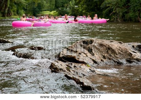 Defocused People Tubing Down River Approach Boulder In Focus