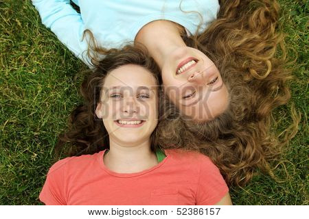 Smiling teenagers friends lying on a grass in a park