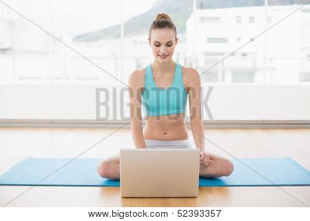 Sporty smiling woman using laptop in bright room